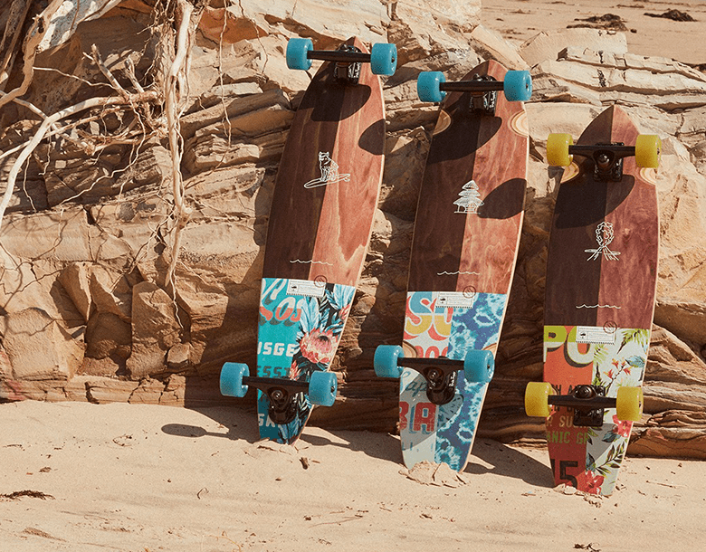 Three skateboards are parked on the beach.