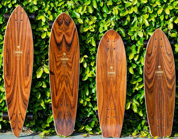 Four wooden skateboards are lined up against a wall.
