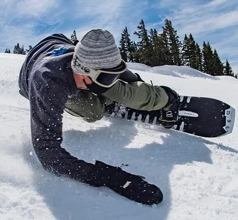 A man laying on the snow with his snowboard.